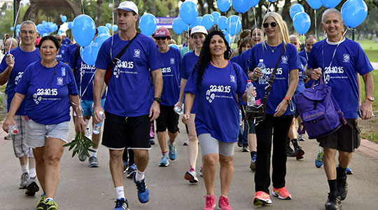 תושבים הולכים בחולצות כחולות אוחזים בלונים בצבע תכלת